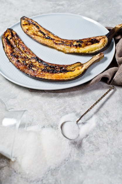 Banane al forno con miele su un piatto grigio.