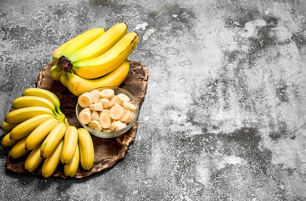 Banane fresche con pezzi di banane a fette in una ciotola. Sulla tavola rustica.