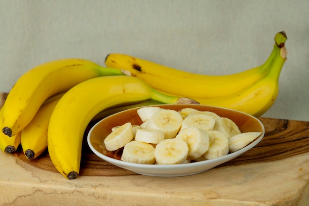 Banane fresche e banane tagliate a pezzi in una ciotola sul tavolo stock photo