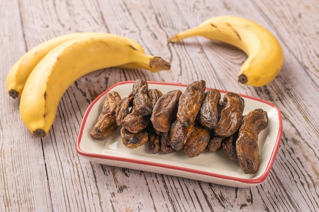 Banane fresche e secche su un tavolo di legno rustico Delizioso spuntino di frutta naturale