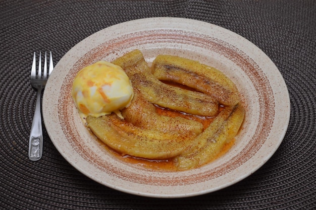 Banane fritte dessert cinese con una ciotola di gelato su uno sfondo scuro