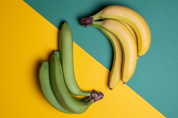 Banane gialle e verdi su una tavola colorata, concetto maturo e non maturo della frutta