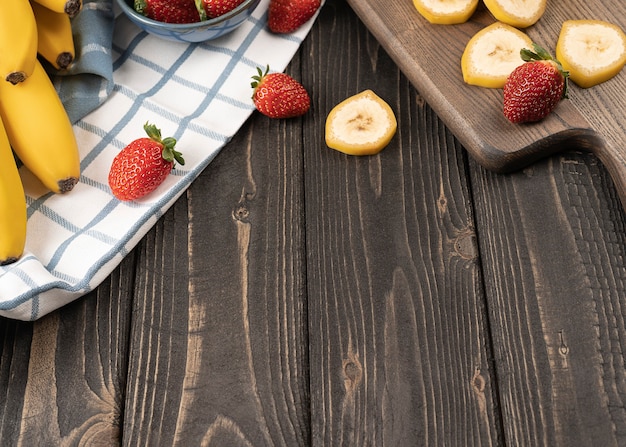 Banane slised e fragole su una tavola di legno si chiudono