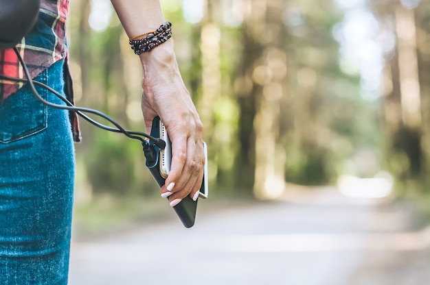 Banca di potere nella mano della ragazza, contro la foresta e la strada.