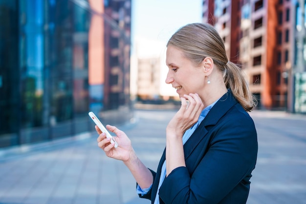 Banchiere femminile di successo che utilizza lo smartphone all'aperto mentre si trova vicino all'ufficio