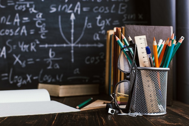 Banco di scuola in aula, con libri sullo sfondo del bordo di gesso con formule scritte