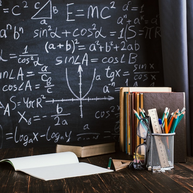 Banco di scuola in aula, con libri sullo sfondo del bordo di gesso con formule scritte