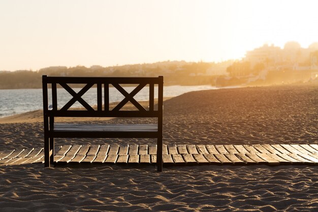 Banco sulla spiaggia al tramonto giallo.