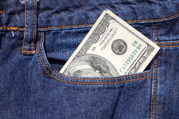 Banconota da cento dollari americani nella tasca dei jeans blu