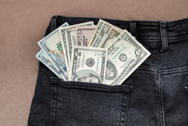 Banconota da cento dollari che esce dalla tasca dei jeans neri