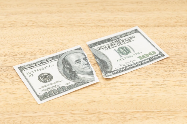 Banconota falsa del dollaro strappata sulla tavola di legno