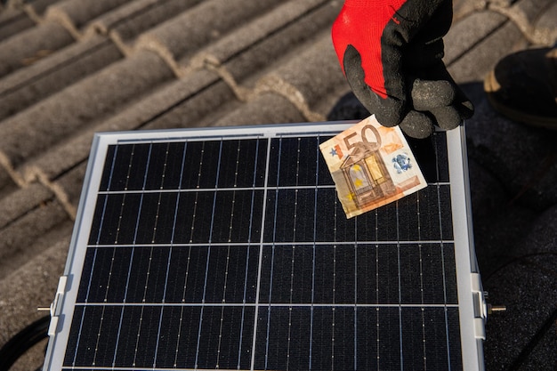 Banconota tagliata vicino a un concetto di pannello solare di inflazione e crisi energetica