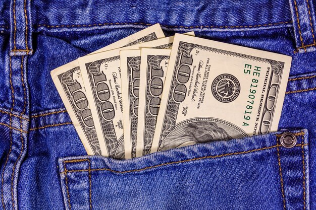 Banconote americane da cento dollari in una tasca dei jeans blu