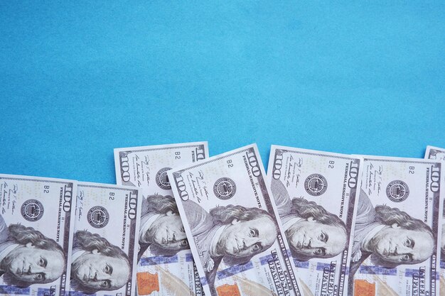 Banconote da cento dollari isolate su sfondo blu
