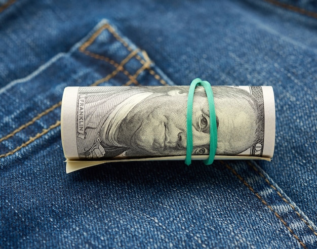 Banconote da un dollaro arrotolate su tessuto jeans