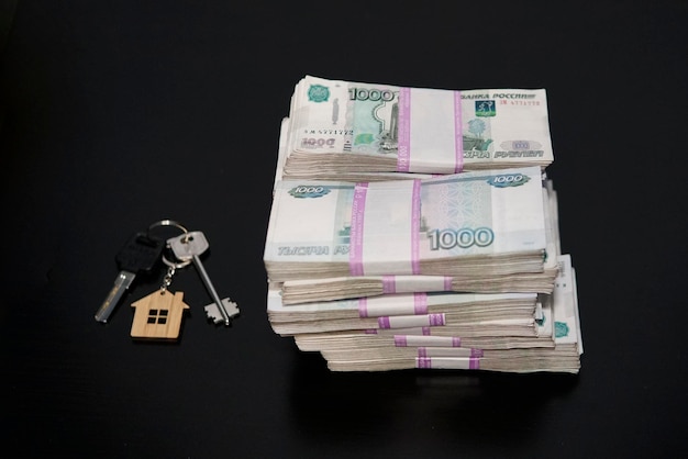 Banconote di rubli russi e chiavi dell'appartamento sul tavolo nero Vendita immobiliare L'affare per la vendita dell'appartamento Concept