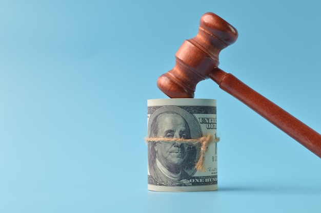 Banconote in denaro e martelletto del giudice isolato su sfondo blu