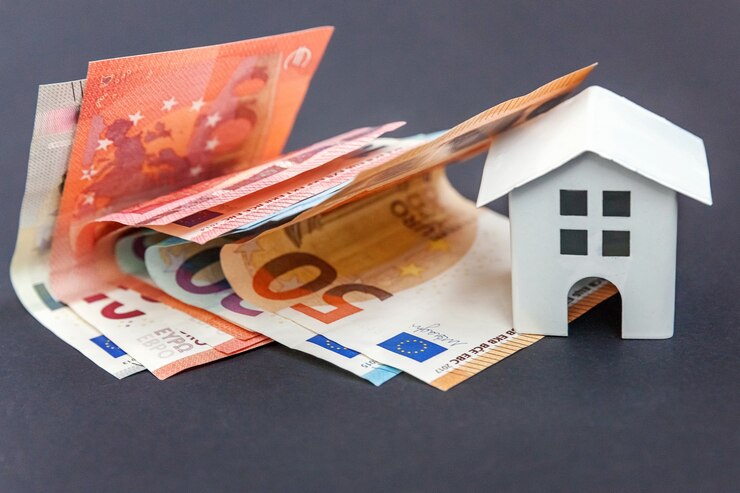 Banconote in euro e simbolica piccola casa giocattolo