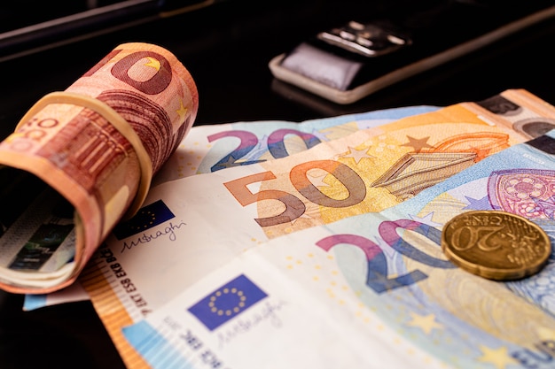 banconote in euro su una scrivania con rotolo di denaro e cucitrice nera