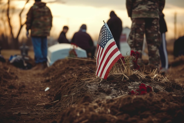 Bandiera americana accanto alla tomba fresca a un funerale militare con soldati e luttuosi sullo sfondo