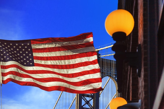 Bandiera americana che ondeggia nel vento ponte di manhattan all'ombra blu new york