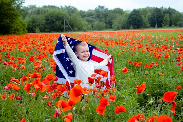 Bandiera americana nelle mani di un bambino tra un campo di papaveri rossi