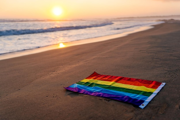 Bandiera arcobaleno LGTBQ sulla riva della spiaggia al tramonto