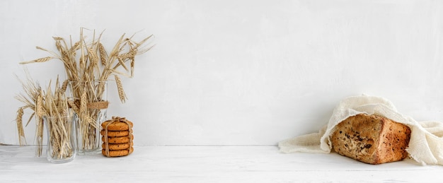 Bandiera bianca della cucina biscotti di farina d'avena pane e spighe di grano su un tavolo bianco