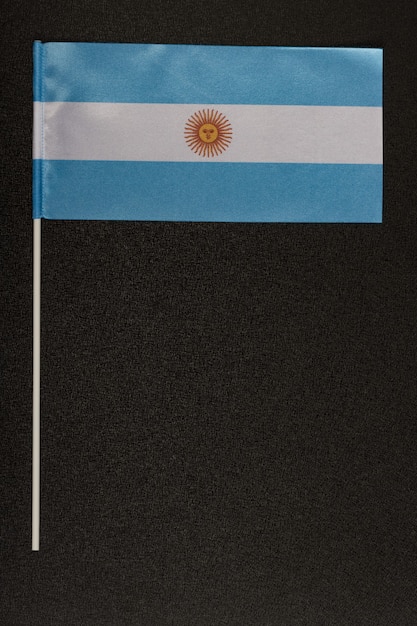 Bandiera da tavolo dell'Argentina su sfondo nero. Bandiera bianco-azzurra con sole. Cornice verticale