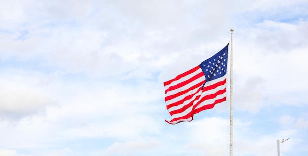 Bandiera degli Stati Uniti che sventola nel vento contro un cielo blu Simbolo di libertà, unità e orgoglio nazionale Perfetto