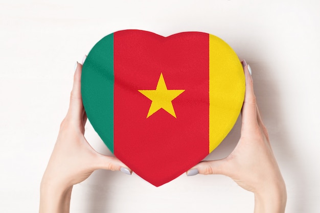 Bandiera del Camerun su una scatola a forma di cuore in mani femminili.