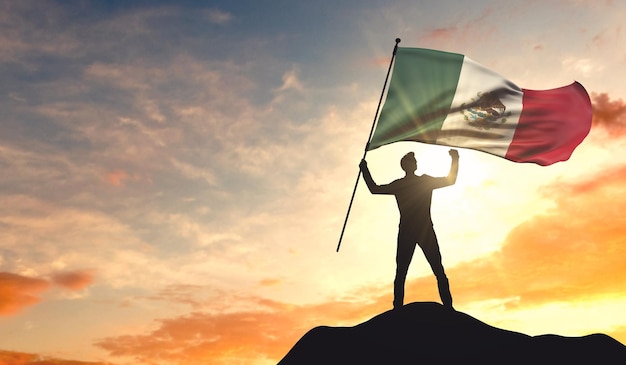 Bandiera del Messico sventolata da un uomo che celebra il successo in cima a una montagna Rendering 3D