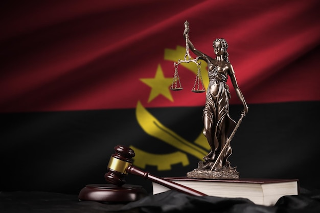 Bandiera dell'Angola con la statua della costituzione della giustizia della signora e martello del giudice su panneggio nero Concetto di giudizio e colpa