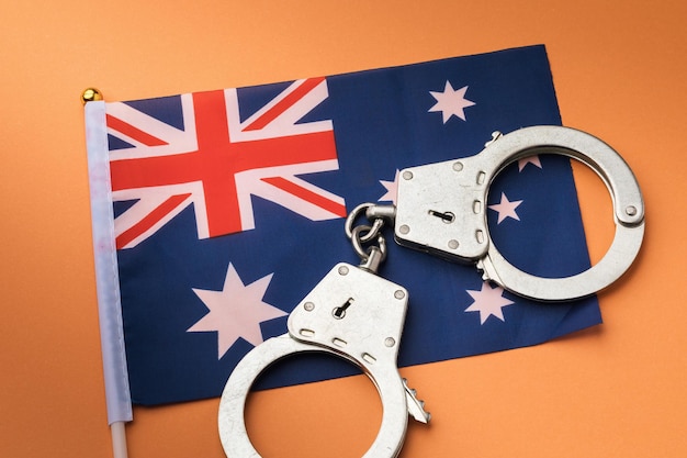 Bandiera dell'Australia e manette sul concetto di sfondo arancione sul tema della criminalità nel paese