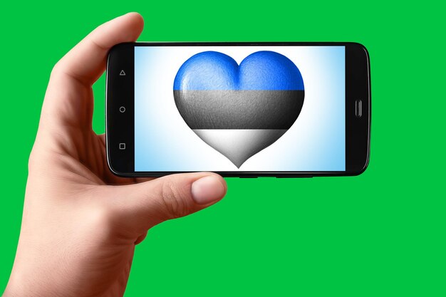 Bandiera dell'Estonia a forma di cuore sullo schermo del telefono Smartphone in mano mostra il cuore della bandiera sullo sfondo hromakey