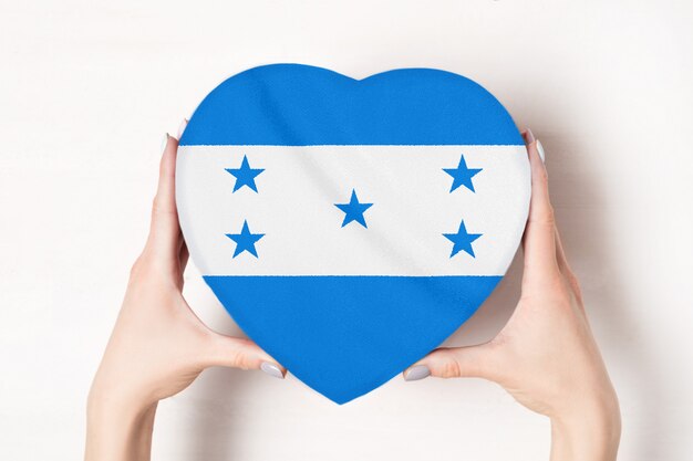 Bandiera dell'Honduras su una scatola a forma di cuore in mani femminili.