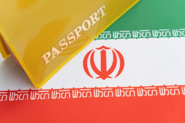 Bandiera dell'iran con passaporto Visto di viaggio e concetto di cittadinanza permesso di soggiorno nel paese un documento giallo con la scritta passaporto è sulla bandiera Vista ravvicinata dall'alto