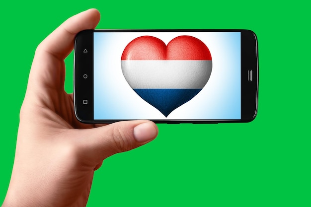 Bandiera dell'Olanda a forma di cuore sullo schermo del telefono Uno smartphone in mano mostra un cuore di bandiera su uno sfondo chroma key