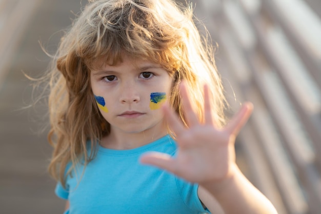 Bandiera dell'Ucraina sulla guancia dei bambini piccolo patriota ucraino fermare la guerra gesti delle mani nessuna guerra fermare la guerra russi