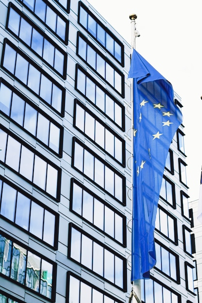 Bandiera dell'Unione europea che sventola davanti al moderno edificio per uffici aziendali simbolo del parlamento eu...