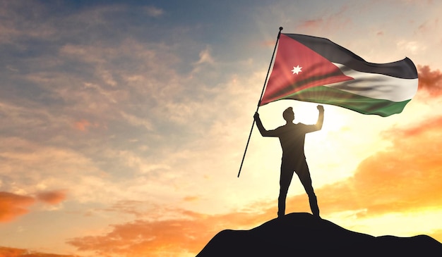 Bandiera della Giordania sventolata da un uomo che celebra il successo in cima a una montagna Rendering 3D