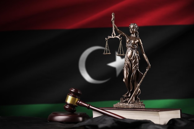 Bandiera della Libia con la statua della costituzione della giustizia della signora e il martello del giudice su drappeggio nero Concetto di giudizio e colpa
