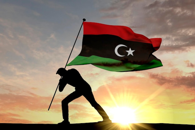 Bandiera della Libia spinta nel terreno da un rendering 3D di silhouette maschile