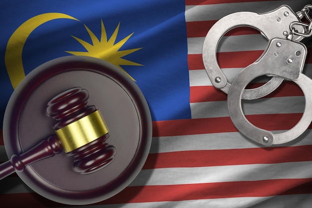Bandiera della Malesia con maglio del giudice e manette in camera oscura Concetto di sfondo penale e punitivo per argomenti di giudizio