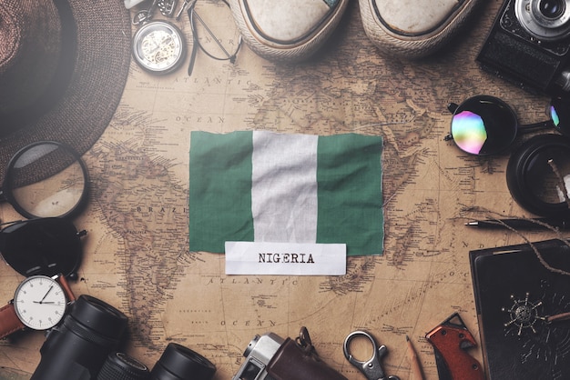 Bandiera della Nigeria tra gli accessori del viaggiatore sulla vecchia mappa vintage. Colpo ambientale