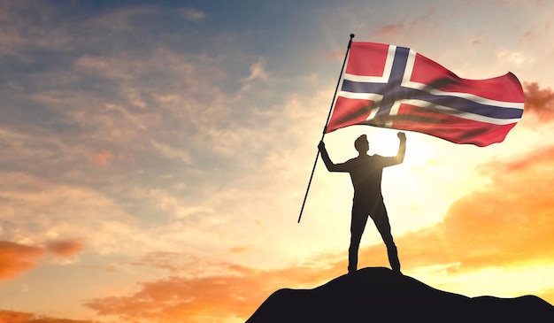Bandiera della Norvegia sventolata da un uomo che celebra il successo in cima a una montagna Rendering 3D
