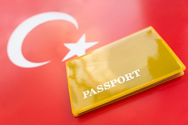 Bandiera della turchia con passaporto Visto di viaggio e concetto di cittadinanza permesso di soggiorno nel paese un documento giallo con la scritta passaporto è sulla bandiera Vista ravvicinata dall'alto