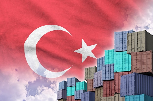 Bandiera della Turchia e grande pila di container di carico marittimo nelle banchine con sfondo celeste
