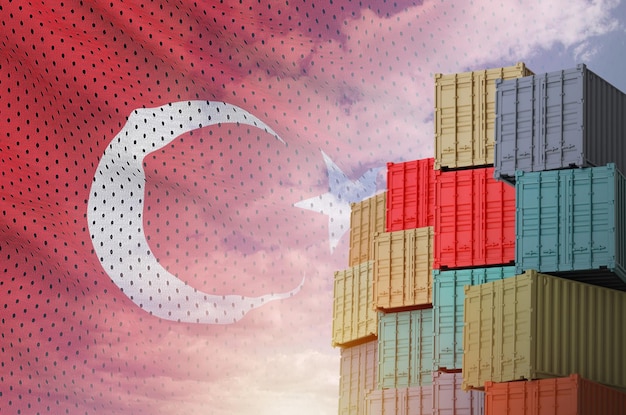Bandiera della Turchia e grande pila di container di carico marittimo nelle banchine con sfondo celeste