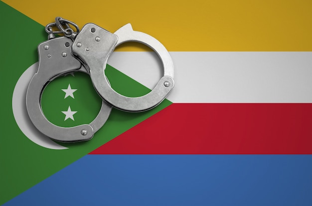 Bandiera delle Comore e manette della polizia. Il concetto di criminalità e reati nel paese